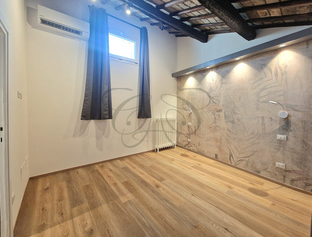 A romantic attic bedroom with sloping beamed ceiling in a charming apartment for rent near Piazza Navona.