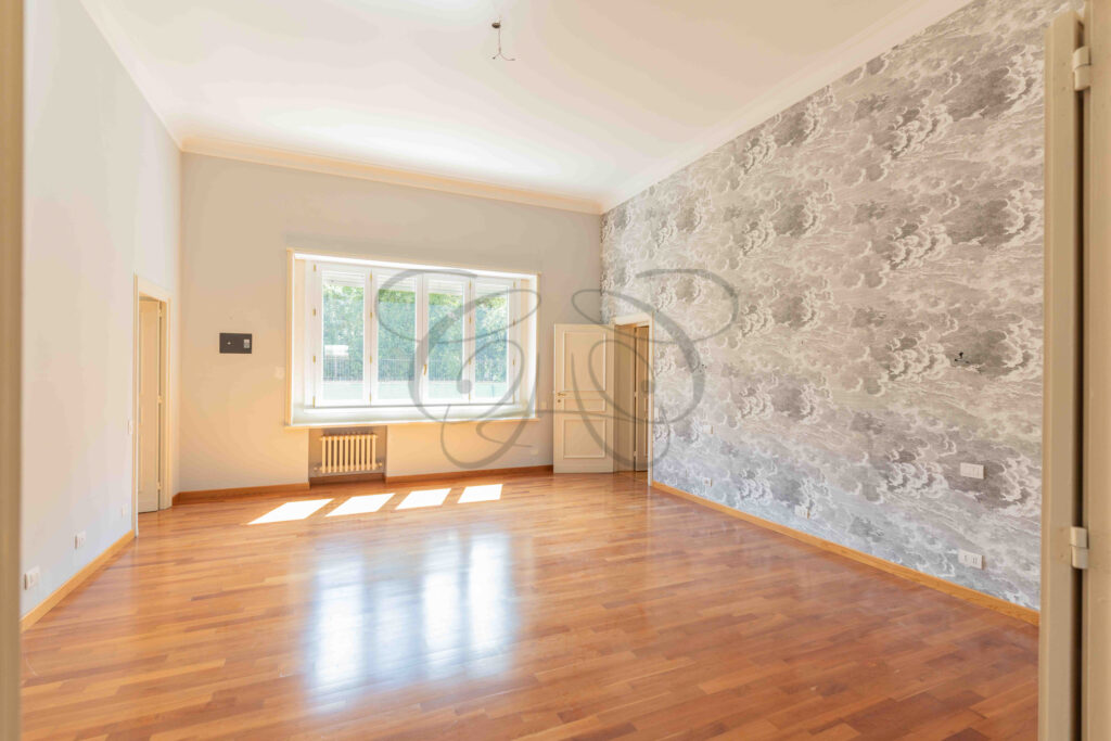 Spaziosa camera da letto padronale con pavimento in parquet e pareti neutre in una proprietà di lusso in vendita a Roma Parioli.