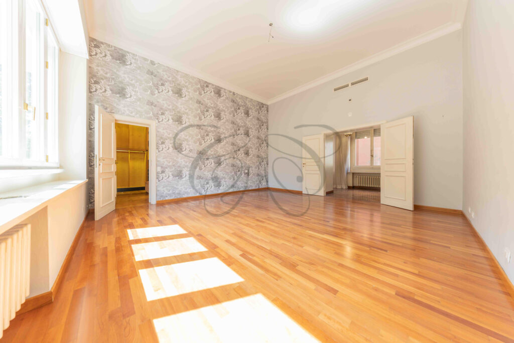 Camera da letto con carta da parati a motivi floreali e pavimento in parquet in un appartamento di lusso a Roma Parioli.