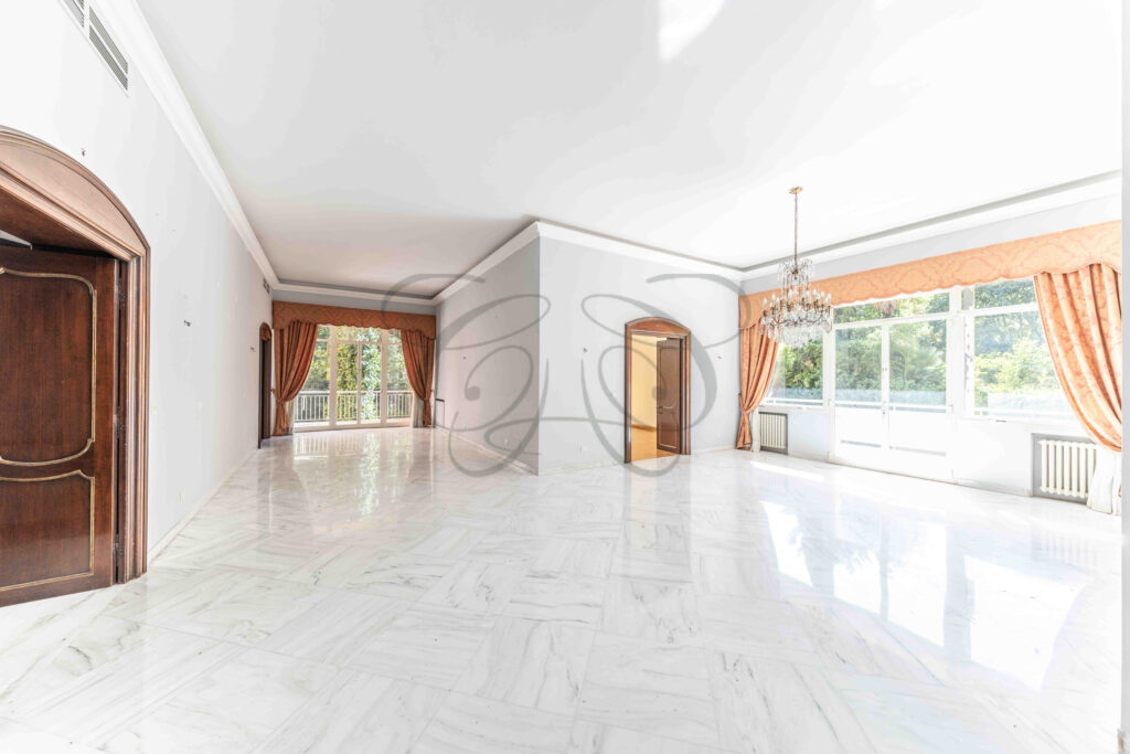 Vista attraverso una porta aperta del salone di rappresentanza di un appartamento di lusso in vendita a Roma Parioli.