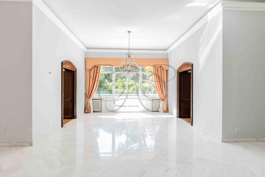 Prospettiva dal secondo salone verso la sala da pranzo formale in un appartamento di lusso a Roma Parioli.