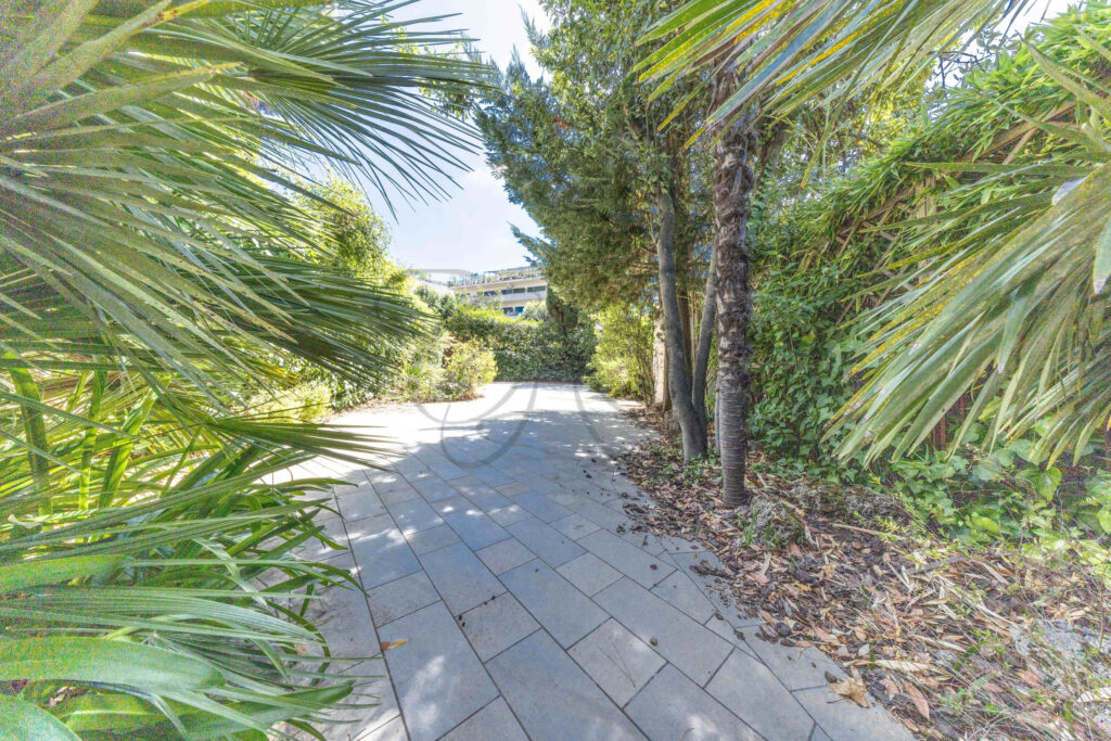 Sentiero in pietra che attraversa il giardino privato di un attico di lusso in vendita nel quartiere Parioli a Roma.