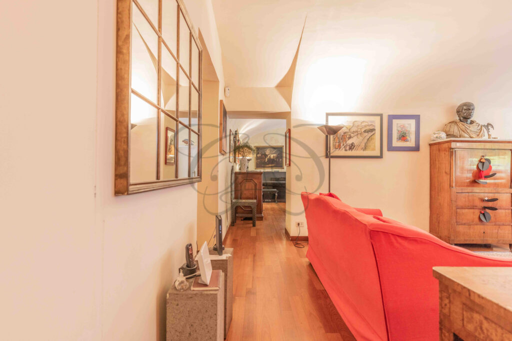 Passageway sitting area with artwork and red sofa - Class & Country Homes.